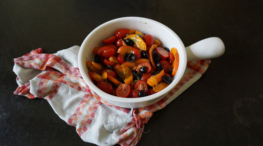 eine Backofenform mit gebackenen Minitomaten, Aprikosenhälften und schwarzen Oliven