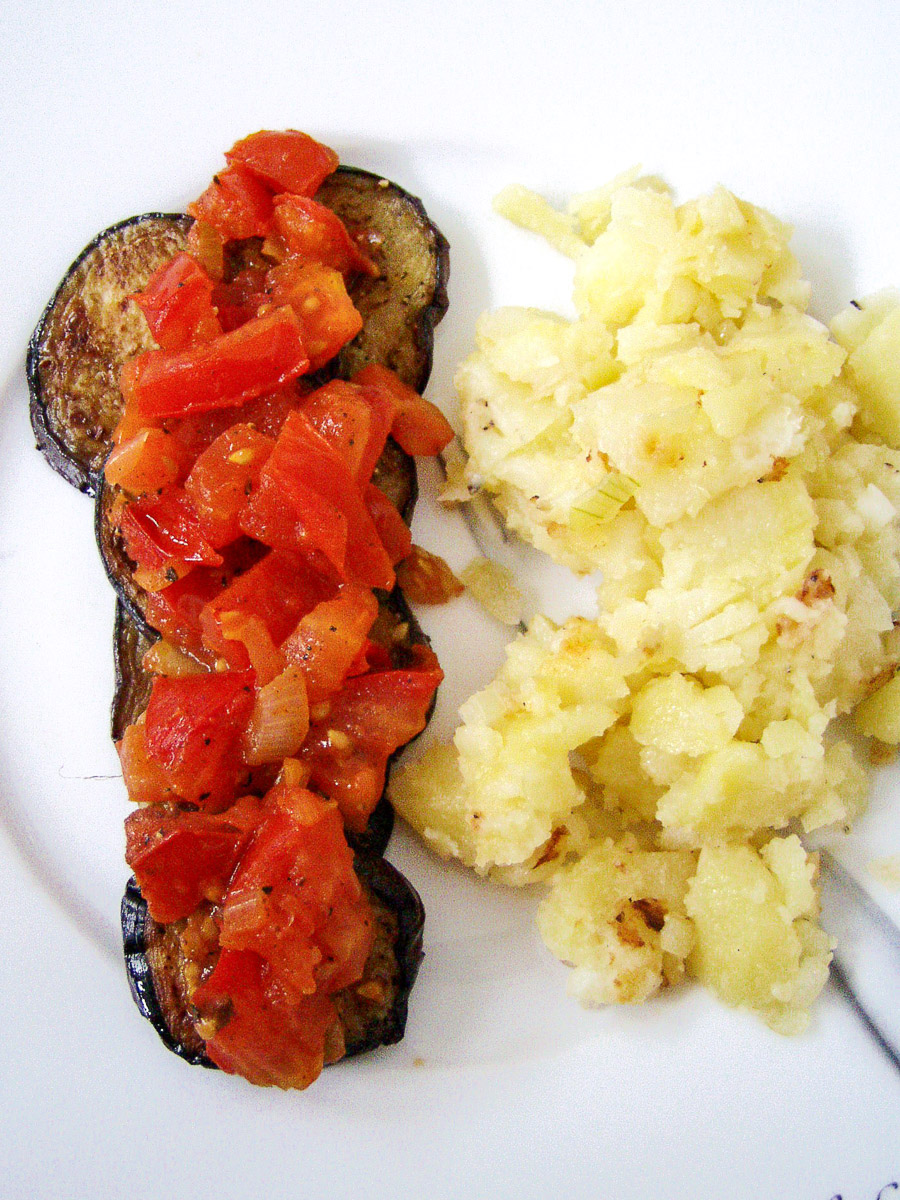 gebratene Zucchinischeiben mit Topping aus Tomaten, daneben Bratkartoffeln