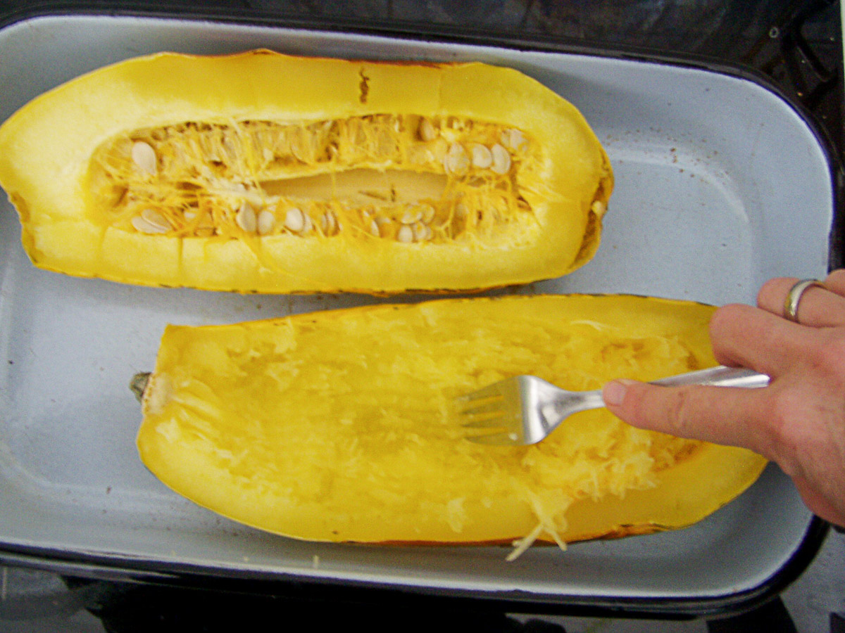 Gabel krazt Fruchtfleisch aus aufgeschnittenem gegarten Spaghettikürbis