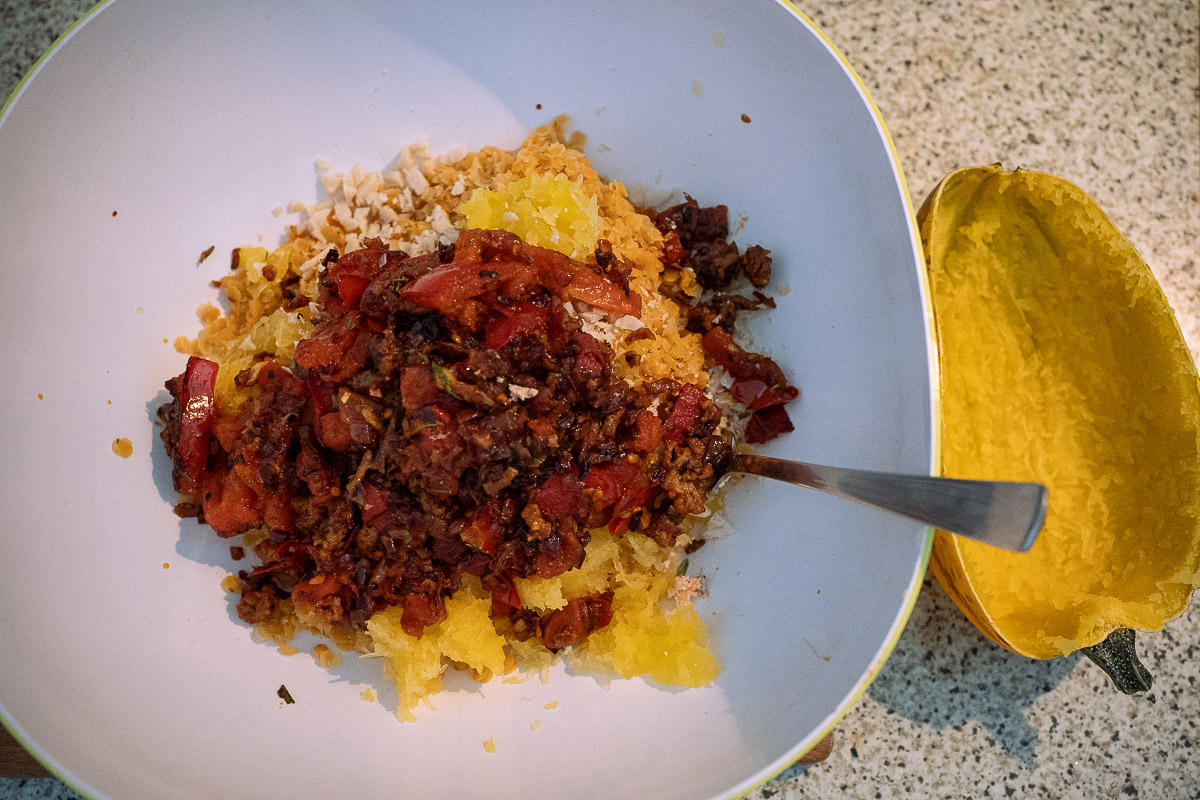 Schüssel mit den Fasern des Spaghettikürbis, gebratenen Tomaten und  Hackfleisch sowie roten Linsen